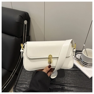 Detail view of a white rectangular flap bag with a premium golden twist lock on a desk