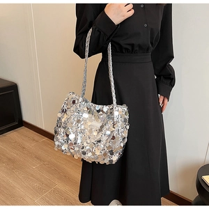 Detail of silver sequin tote bag featuring braided handles and brand logo tag