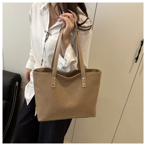 Detail of hand-woven texture on khaki tote bag with reinforced silver hardware straps
