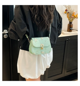 Detail of mint green saddle bag featuring delicate floral embroidery and gold metal buckle