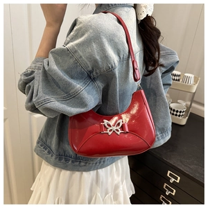 Détail du sac rouge en cuir brillant avec un fermoir papillon métallique élégant