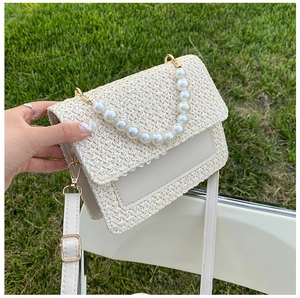 Detail of cream woven handbag with large pearl handle and adjustable shoulder strap