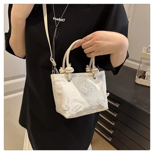 Détail d'un sac en dentelle ivoire avec broderie papillon 3D et poignée nouée