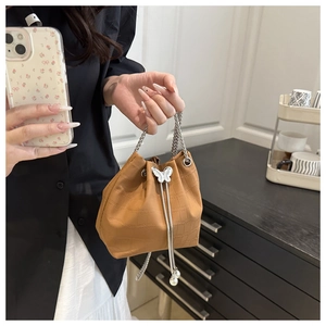 Detail of brown crocodile pattern bucket bag with silver butterfly charm and pearl tassel