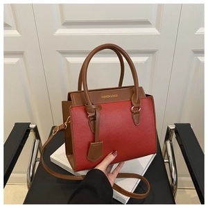 Detail of red litchi grain faux leather tote with brown handles and fashion logo