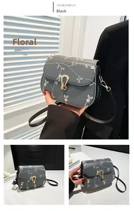 Detailed view of grey shoulder bag with white floral embroidery and gold horseshoe buckle