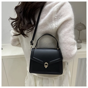 Detail of minimalist black leather crossbody bag with gold ring buckle on model