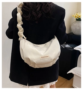 Detail of white pleated nylon crossbody bag featuring stylish fashion label and ruffles