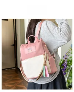 Detail of pink and white nylon backpack featuring colorful striped straps and tassels