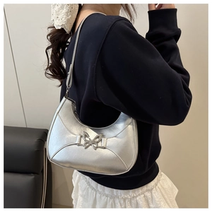 Sac croissant argenté avec breloque papillon porté à l'épaule pour un style moderne