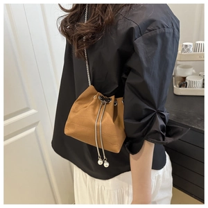 Detail of brown bucket bag with pearl drawstring and silver chain strap on a model