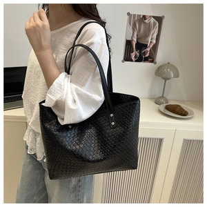 Close-up of black woven tote bag with silver metal studs and dual shoulder straps
