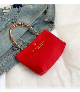 Close-up of a red mini handbag with colorful beaded handles and golden logo text