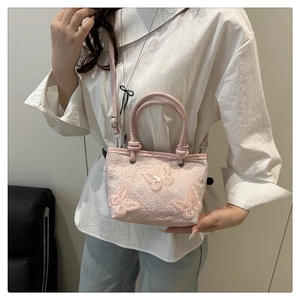 Détail du mini sac seau en dentelle rose avec broderie papillon 3D et bandoulière amovible