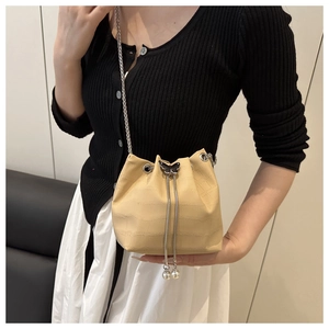 Detail of cream drawstring bucket bag with crocodile texture and butterfly hardware