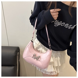 Sac hobo demi-lune rose métallisé avec boucle papillon argentée porté par un modèle