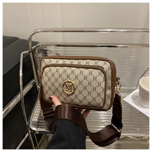Detail of vintage monogram crossbody bag with gold M logo and brown leather trim