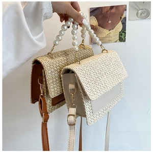 Detail of straw woven handbag with pearl handle and leather trim in two colors