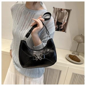 Détail du sac croissant noir avec une boucle métallique en forme de papillon argenté