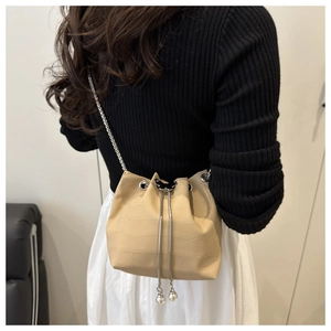 Detail of beige crocodile pattern bucket bag with pearl drawstring and metal chain
