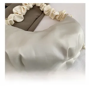 Detailed close-up of ruched texture and fashion label on off-white crossbody cloud bag
