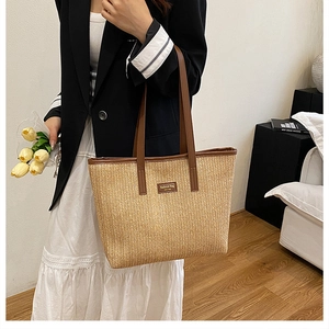 Close-up of woven straw tote bag featuring brown leather trim and chic logo patch