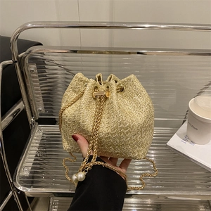 Fashionable beige woven bucket bag with gold chain strap and pearl pendant detail