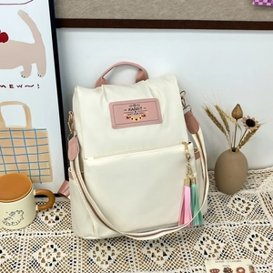 Retro cream white backpack with pink accents and colorful tassel on lace background