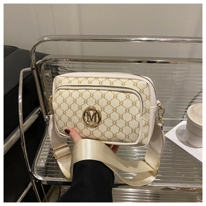 Detail of crossbody bag with vintage monogram pattern and gold M letter hardware buckle