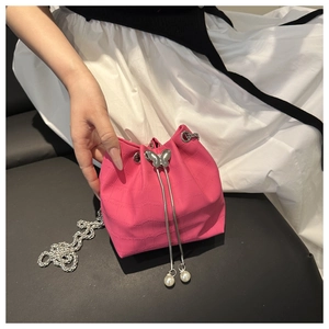 Detail of pink croc-embossed bucket bag with silver butterfly buckle and pearl charms