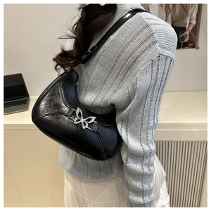 Détail du sac hobo avec boucle papillon argentée et texture en cuir brillant plissé