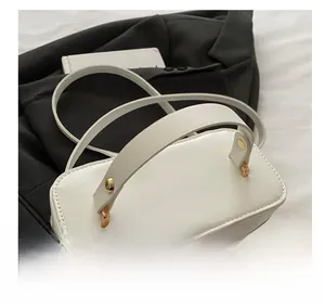 Detail of the white box bag featuring a thick top handle and golden circular logo hardware