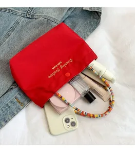 Detail of red canvas tote with beaded handle showing interior storage capacity