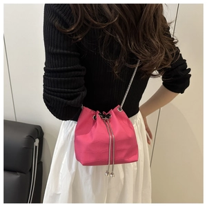 Detail of fuchsia crocodile pattern bucket bag with chain strap and butterfly clasp