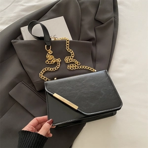 Minimalist black chain crossbody bag with glossy leather and gold metal buckle detail