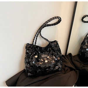 Close-up of black sequined tote bag featuring woven rope handles and reflective details