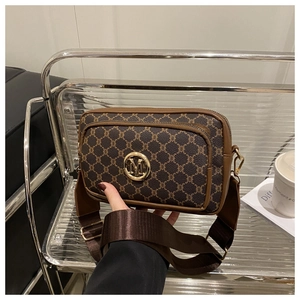Detail of vintage patterned crossbody bag with gold M logo and wide fabric strap