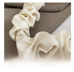 Detail of soft cream pleated nylon shoulder strap with a satin-like finish and fluffy texture