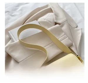 Detailansicht der cremefarbenen Ledertasche mit breitem Gurt und goldener Schließe