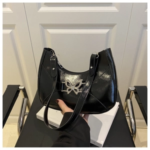 Détail du fermoir papillon en métal argenté sur un sac à bandoulière noir brillant
