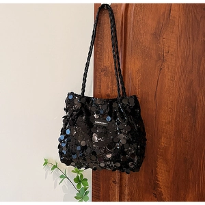 Close-up of shiny black sequins and the Fashion & Bags brand tag on a woven tote bag
