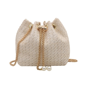 Straw drawstring bucket bag with gold chain and pearl accents in minimalist summer style