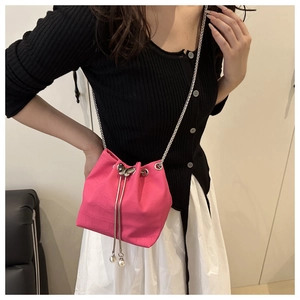Pink crocodile-textured bucket bag featuring a silver butterfly clasp and pearl drawstring