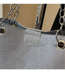 Detail der blauen Denim-Tragetasche mit silberner Metallkette und Ösenverstärkung