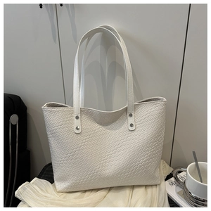Detail of white faux leather tote bag with snakeskin texture and silver rivet accents
