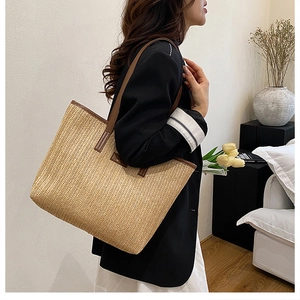 Close-up of woven straw tote bag with brown leather handles and side label detail