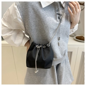 Detail of black croc-embossed bucket bag with butterfly metal drawstring and chain strap