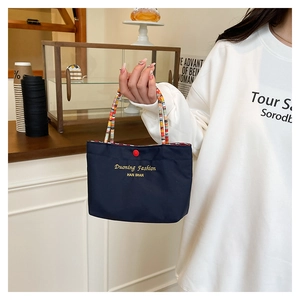 Detail of navy blue nylon mini bag with colorful beaded handle and red button closure