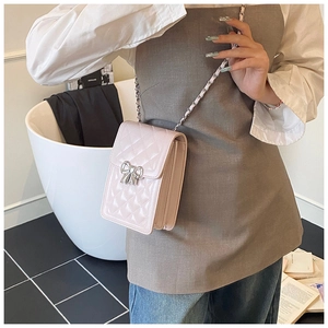 Detail of pink quilted phone bag with silver bow buckle and chain strap shown on model