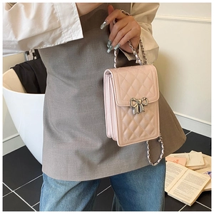 Detailed view of pink quilted crossbody bag with silver bow buckle and chain strap